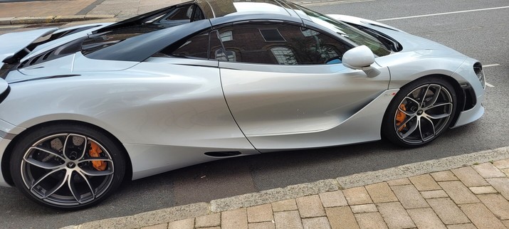 Shiny silver mclaren road sports car. It looks like a spaceship driven by perhaps an angel.