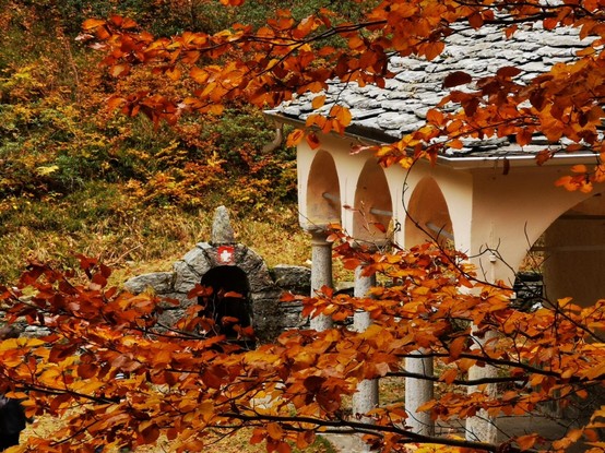 A house seen through autumn colored trees in Swiss alps