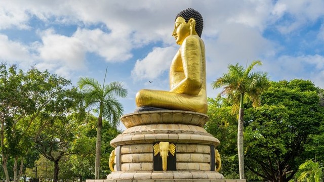 Large gold Buddha statue outside in Sri Lanka.
